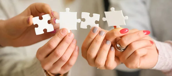People holding pieces of jigsaw puzzle, closeup