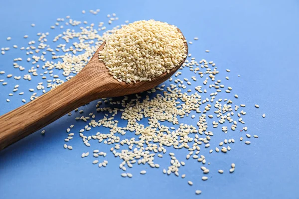 Mavi arka planda susam tohumlu tahta kaşık, yakın plan.