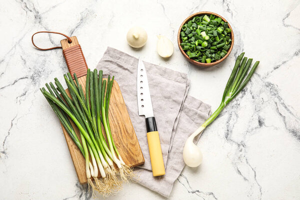 Composition with fresh green onion and knife on light background