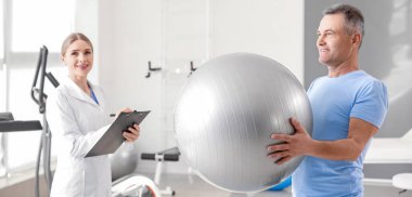 Olgun hasta rehabilitasyon merkezinde topa uygun egzersizler yapıyor.