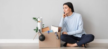 Üzgün kovulmuş kadın ışık duvarının yanında oturuyor.