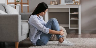 Depresyondaki genç kadın evde yerde oturuyor.