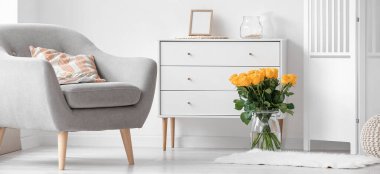 Koltuğu, çekmecesi ve çiçek buketi olan modern oturma odası.