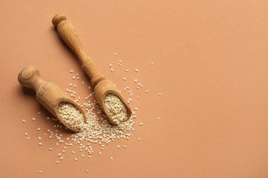 Renk arkaplanında susam tohumları olan tahta kepçeler