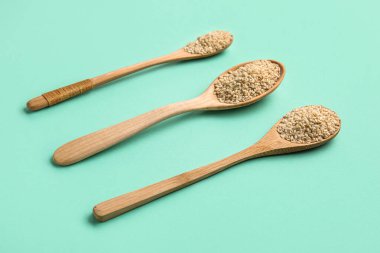 Yeşil arka planda susam tohumlu tahta kaşıklar.