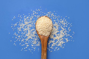 Mavi arka planda susam tohumlu tahta kaşık, yakın plan.