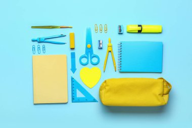 Yellow pencil case with school stationery on blue background