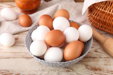 Hafif ahşap arka planda taze tavuk yumurtası kasesi