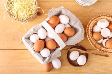 Tavuk yumurtası ve ahşap zemin üzerinde kabuk dolu sepet.