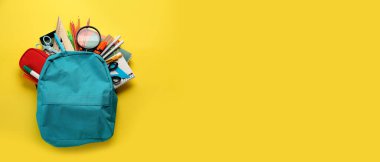 Sarı arkaplanda okul çantası ve kırtasiye malzemesi ve metin için yer var