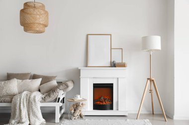 Boş çerçeveli modern şömine, ışık duvarının yanındaki masa ve kanepe.