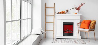 Modern şöminesi, koltuğu ve sonbahar dekoru olan ışık odasının içi