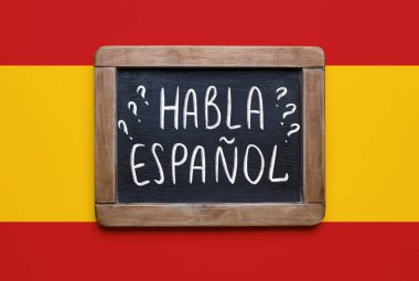 Chalkboard with text HABLA ESPANOL? (DO YOU SPEAK SPANISH?) on flag of Spain