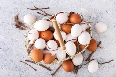 Tavuk yumurtaları, tüyler ve arka planda ağaç dalları olan sepet.