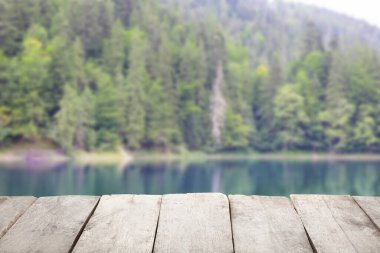Yeşil ormandaki gölün yanındaki boş ahşap masa. Tasarım için model
