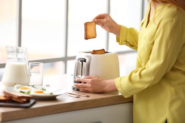 Olgun kadın mutfakta lezzetli tost yapıyor.