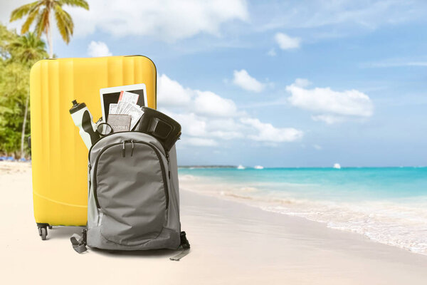 Чемодан и рюкзак с пляжными аксессуарами на песке. Концепция путешествия