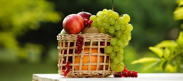 テーブルの上に新鮮な果物とウィッカーバスケット屋外 — ストック写真