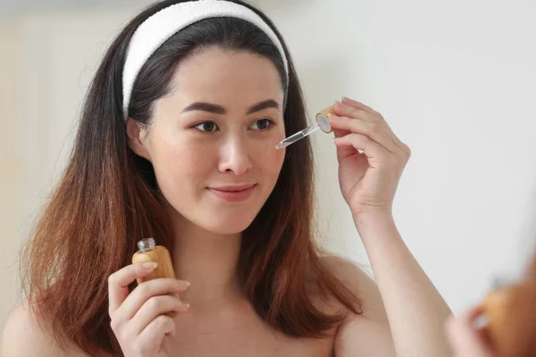 Young Asian Woman Using Cosmetic Serum Bathroom — Stockfoto