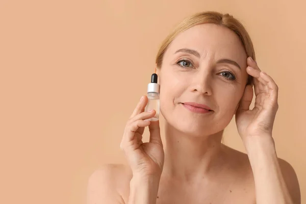 Mature Woman Cosmetic Serum Beige Background — Stockfoto
