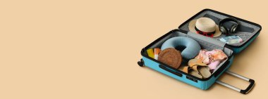 Turist eşyalarıyla dolu bavulu bej arka planda aç ve mesaj için yer aç.