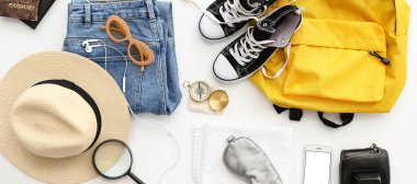 Beyaz arka planda seyahat etmek için aksesuarlar ve giysiler