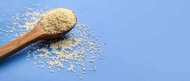 Mavi arkaplanda susam tohumlu tahta kaşık ve metin için boşluk