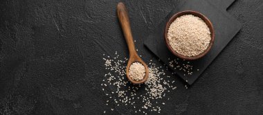 Koyu arkaplanda susam tohumlu kase ve kaşık metin için boşluk