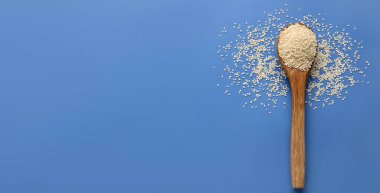 Mavi arkaplanda susam tohumlu tahta kaşık ve metin için boşluk