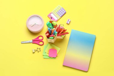 Sarı zemin üzerinde alarm saati olan farklı kırtasiye seti