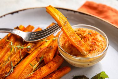 Lezzetli pişmiş havuçlu çatal ve bir kase sos, yakın plan.