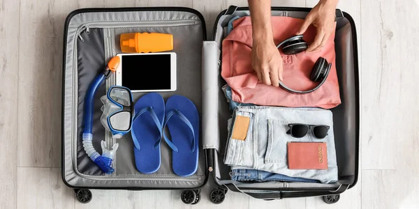 Man packing suitcase at home, top view. Travel concept