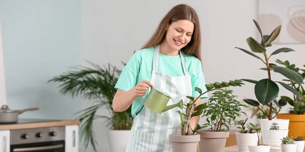 Young Woman Watering Houseplants Home — стоковое фото