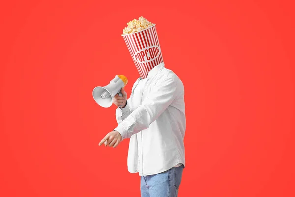Fiatalember Egy Vödör Ropogós Popcornnal Feje Helyett Megafon Vörös Háttéren — Stock Fotó