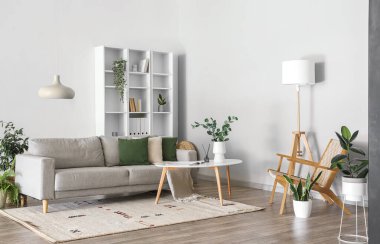 Gri kanepe, masa ve raf ünitesi olan aydınlık oturma odasının içinde.