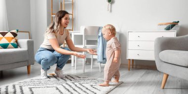 Mother teaching her cute baby to walk at home