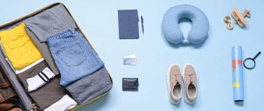 Mavi arka planda bavul ve seyahat aksesuarları, üst görünüm