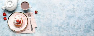 Çilekli tarçınlı tabak ve mavi arka planda bir fincan çay.