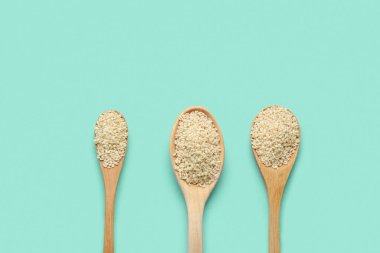 Yeşil arka planda susam tohumlu tahta kaşıklar.