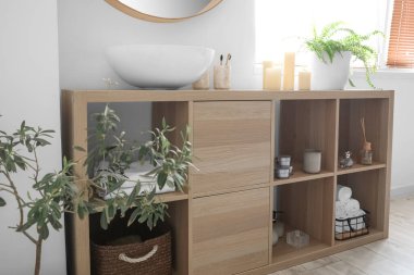 Lavabosu ve banyo aksesuarları olan ahşap raf ünitesi.