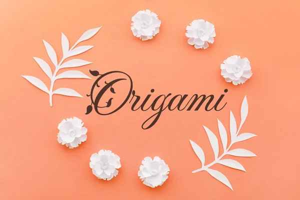 Beautiful handmade paper flowers, tropical leaves and word ORIGAMI on color background