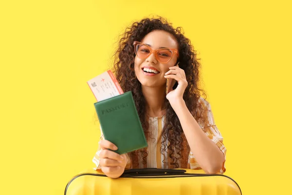 Młoda Afroamerykanka Paszportem Walizką Rozmawiająca Przez Telefon Komórkowy Żółtym Tle — Zdjęcie stockowe