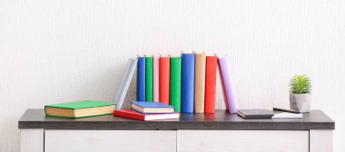 Many books on table near light wall