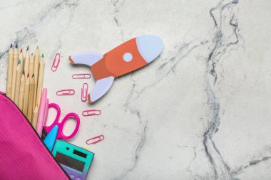 Okul kırtasiyesi ve arka planda kağıt roketli kalem kutusu