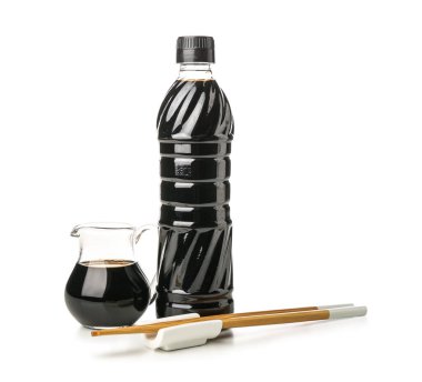 Beyaz arka planda yemek çubukları olan bir şişe soya sosu.