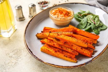 Lezzetli fırında havuç, yeşillik ve sos tabağı.