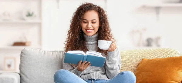 Young African American Woman Cup Tea Reading Book Sofa Home — Stock Photo, Image