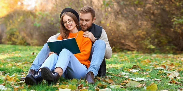 Young Couple Sitting Grass Reading Book Autumn Park — Fotografia de Stock