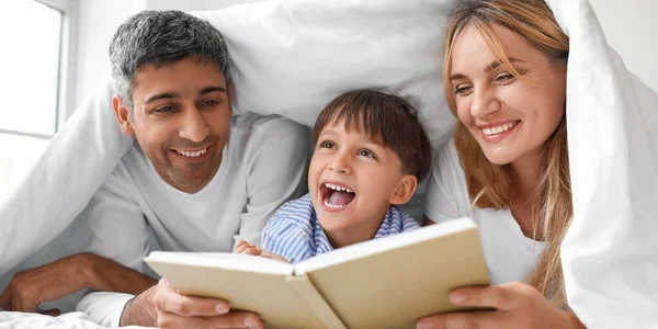 Boldog Szülők Könyvet Olvasnak Kisfiuknak Ágyban — Stock Fotó