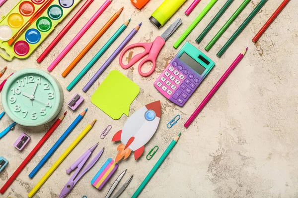 Paper rocket with school stationery and alarm clock on light background